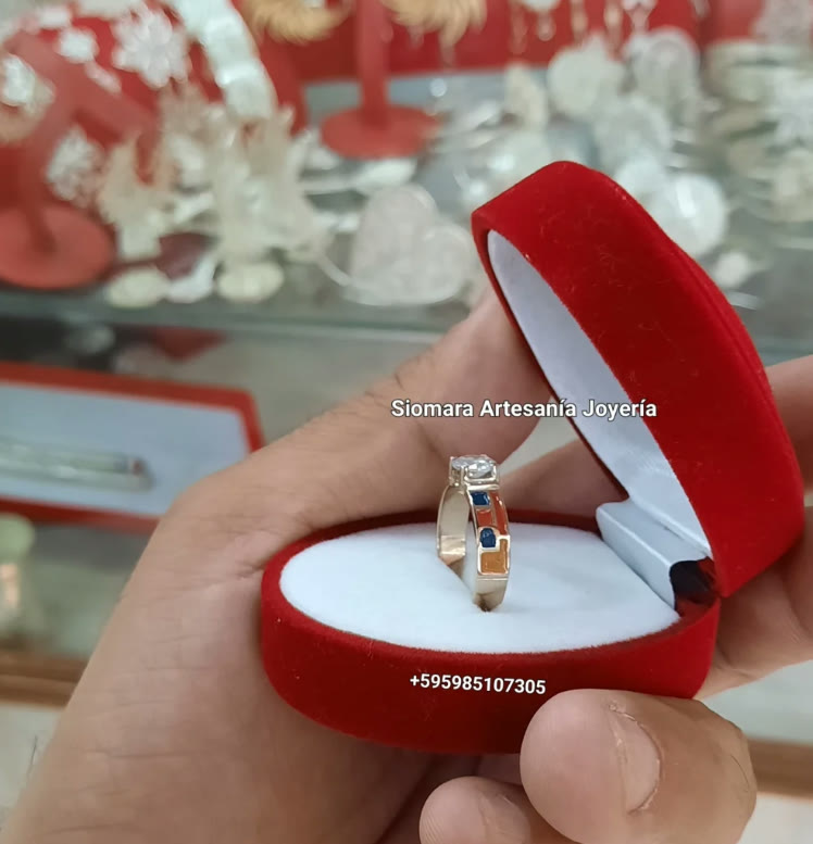 Anillo con piedras azules en estuche rojo, sostenido en la mano